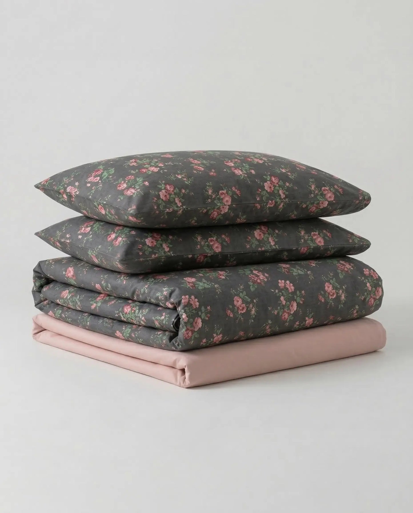 Black floral cotton duvet cover set folded with pillowcases and blush sheet, luxury botanical bedding by DORMÉ Studio