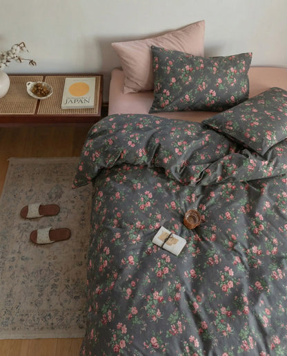 Top view of black floral duvet cover set with soft draping fabric, pink botanical print and neutral bedroom styling