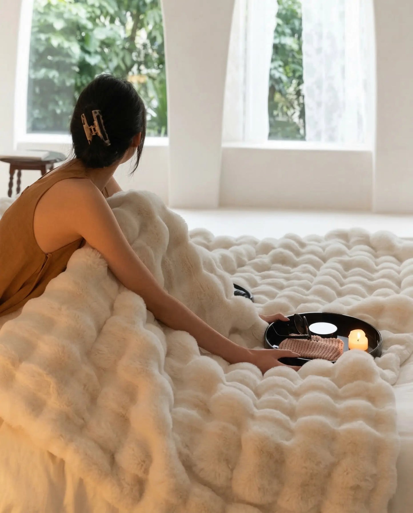 DORMÉ Studio Marshmallow Ultra Plush Blanket styled across bed with candle tray and magazine for luxury bedroom aesthetic.