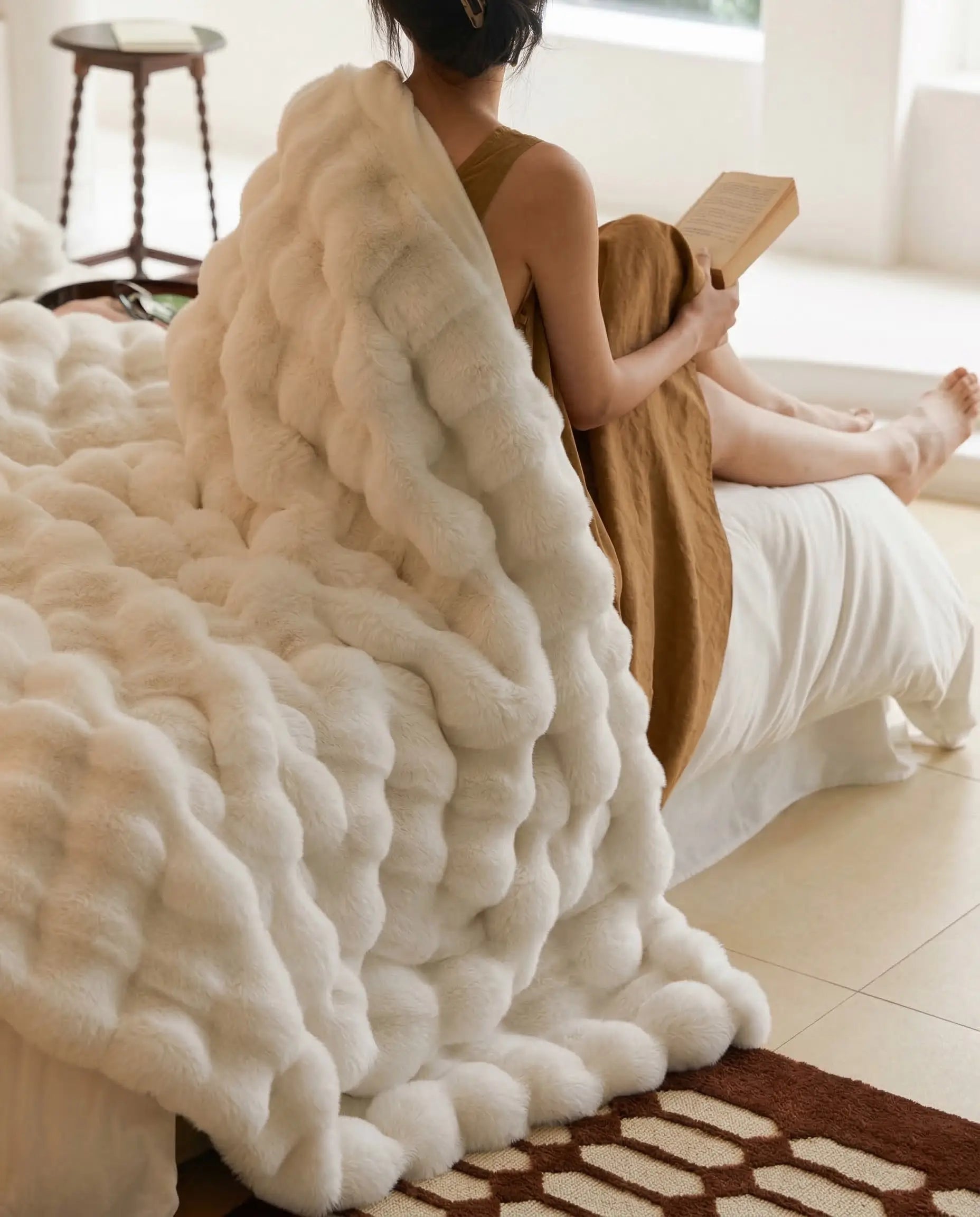 DORMÉ Studio Marshmallow Ultra Plush Blanket cuddled up on a woman, creating a warm luxury bedroom mood.