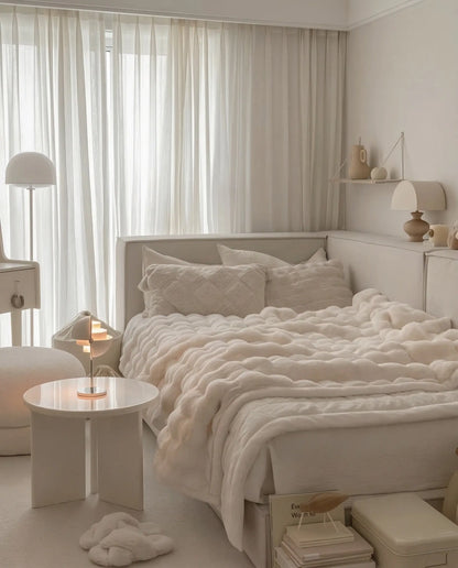 Woman relaxing with DORMÉ Studio Marshmallow Ultra Plush Blanket draped over bed highlighting thick cloud-like plush texture.