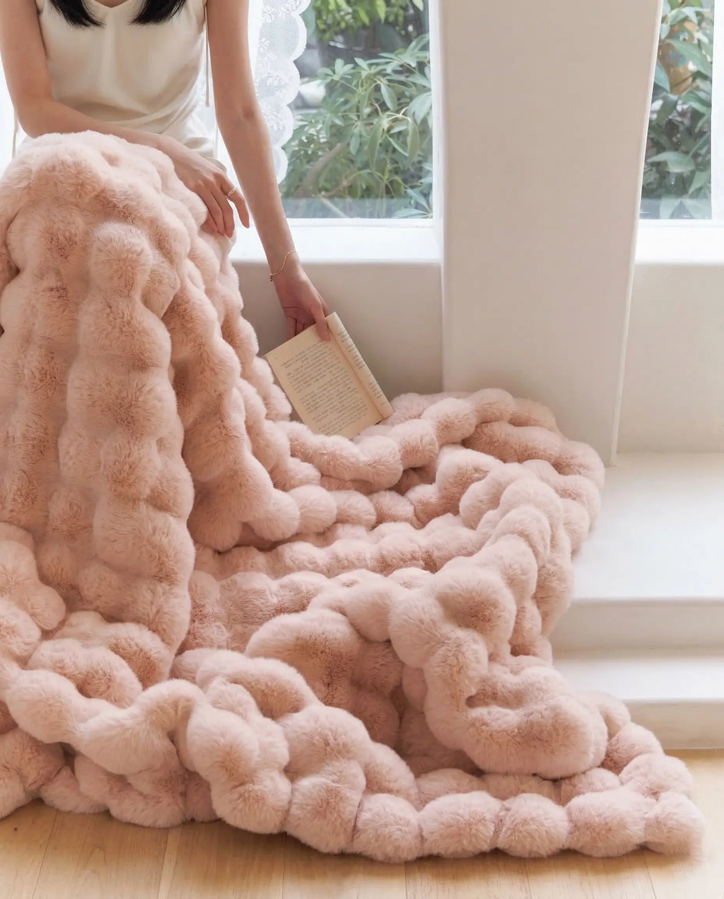 DORMÉ Studio Marshmallow Ultra Plush Blanket pink plush texture cascading across floor near window.