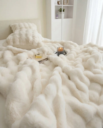 DORMÉ Studio Marshmallow Ultra Plush Blanket covering bed while woman relaxes beside tray with candle and accessories.
