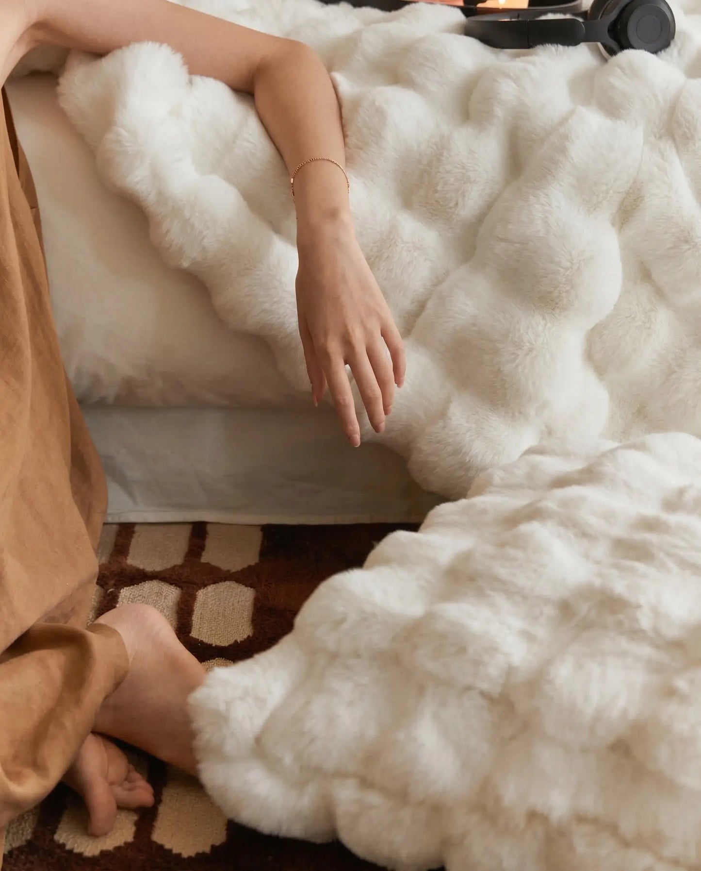 Hand lifting DORMÉ Studio Marshmallow Ultra Plush Blanket revealing cloud like plush texture and luxurious softness.