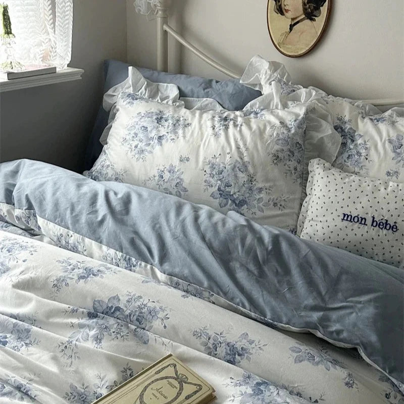 Bedroom with floral bedding and decorative pillows, featuring a window and wall art.